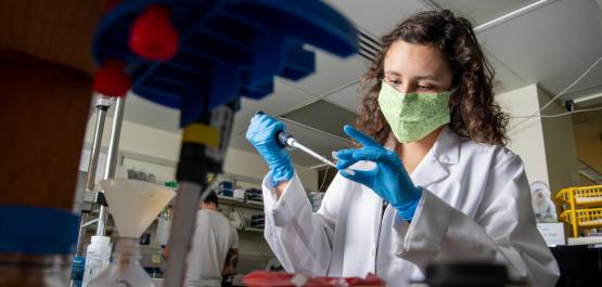 一名女学生戴着口罩在实验室里做科学实验